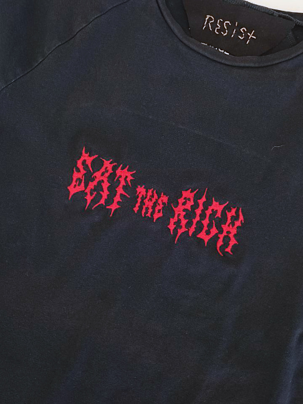 Schwarzes T-Shirt mit roter Schrift in stacheliger Schriftart 'EAT the RICH' auf der Vorderseite und 'RESIST' am Kragen Black T-shirt with red spiky text 'EAT the RICH' on the front and 'RESIST' on the collar 