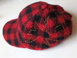 Rote und schwarz karierte Mütze mit gelber Stickerei in Form eines Blattes Red and black checkered cap with yellow leaf-shaped embroidery 