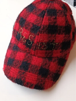 Kappe mit rot-schwarz kariertem Muster und goldfarbener Stickerei auf der Vorderseite Cap with red and black checkered pattern and gold-colored embroidery on the front 