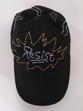 Schwarze Baseballkappe mit der weißen Stickerei 'Resist' in einer gelben, gezackten Umrandung auf der Vorderseite Black baseball cap with white embroidered word 'Resist' inside a yellow jagged outline on the front 