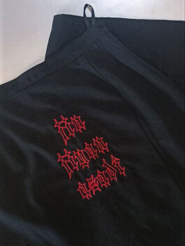Schwarzer Rock mit roter Stickerei in gotischer Schrift 