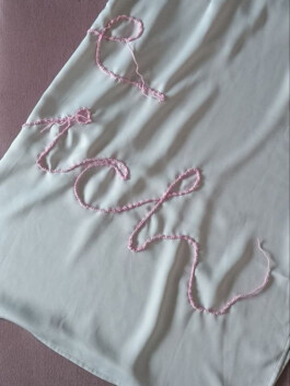 Hellgraues Kleid mit gehäkeltem Schriftzug in rosa Garn