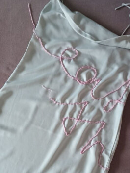 Hellgraues Kleid mit dünnen Trägern und rosafarbenen gehäkeltem Schriftzug als Verzierung