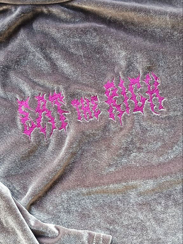 Metallisch schimmernder Pullover mit pinker Schrift in verzerrter Schriftart